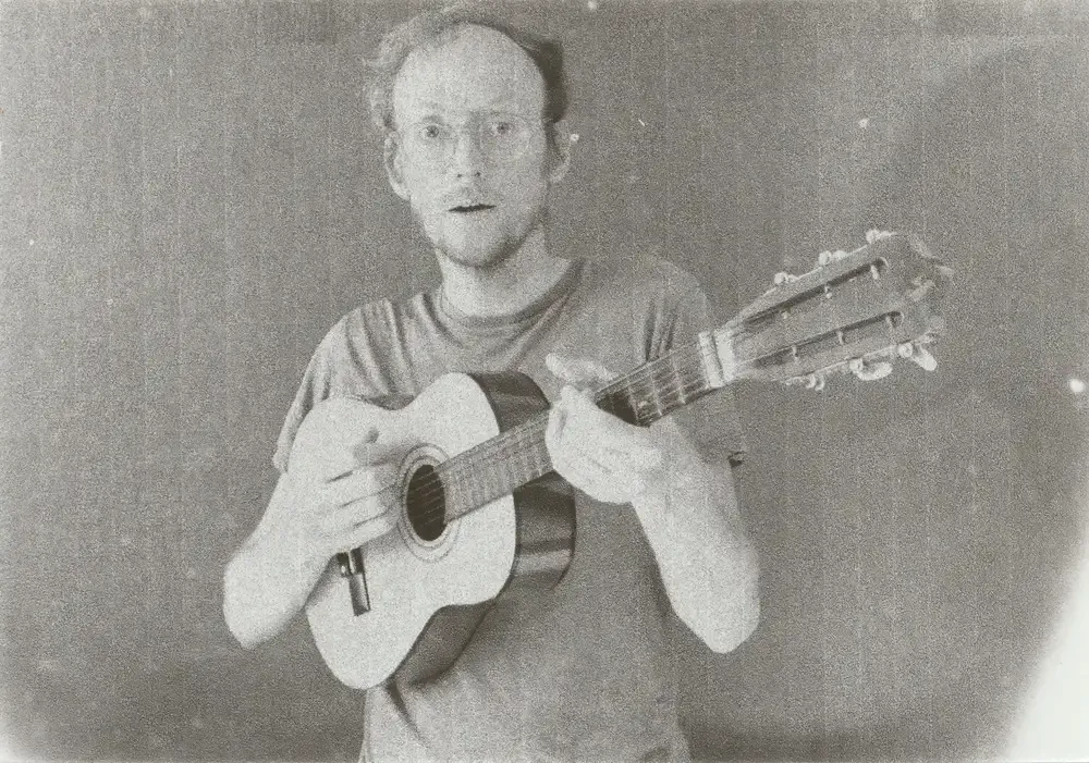 Adam Howard tenant une guitare face à l’objectif